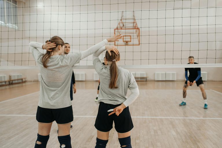 Volleyball players planning strategy during an indoor game, showing teamwork and communication.