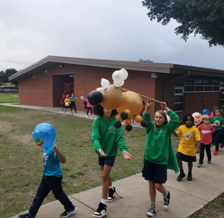 Saker House Leaders lead first grade students in parade.