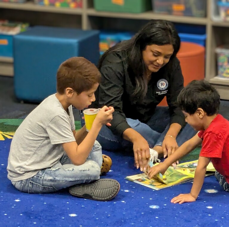 This is a picture of Academic Facilitator, Melissa Davis, reading to two students on FLA's Literacy Night