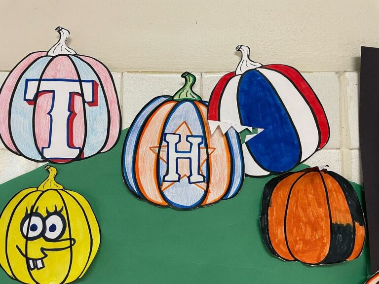 pumpkins colored in Astros theme is being eaten by a paper pumpkin in Rangers colors