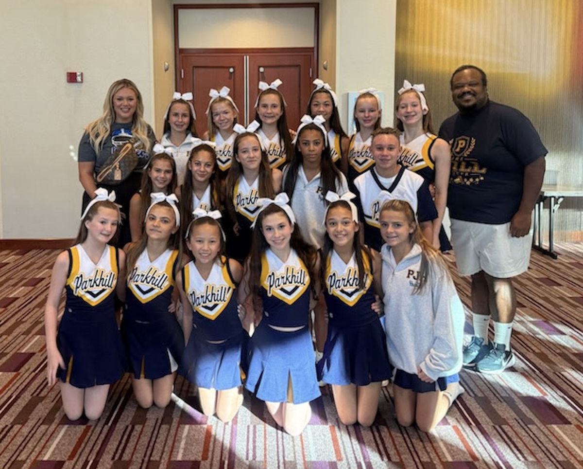 Photo of cheerleaders in uniform posing with their principal and coach