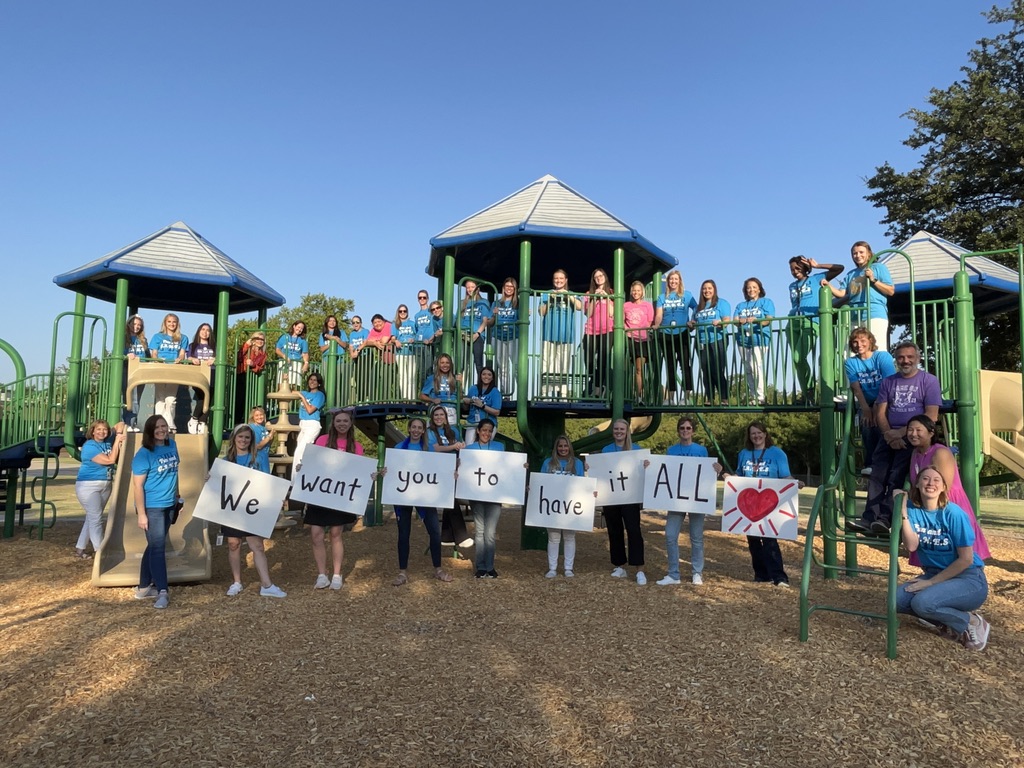 teachers on the playground holding signs saying "We want you to have it all!"
